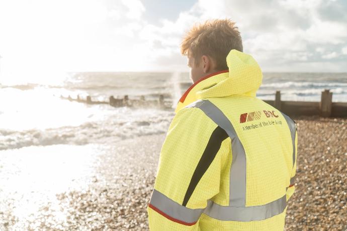 man in yellow and white jacket standing on beach during daytime